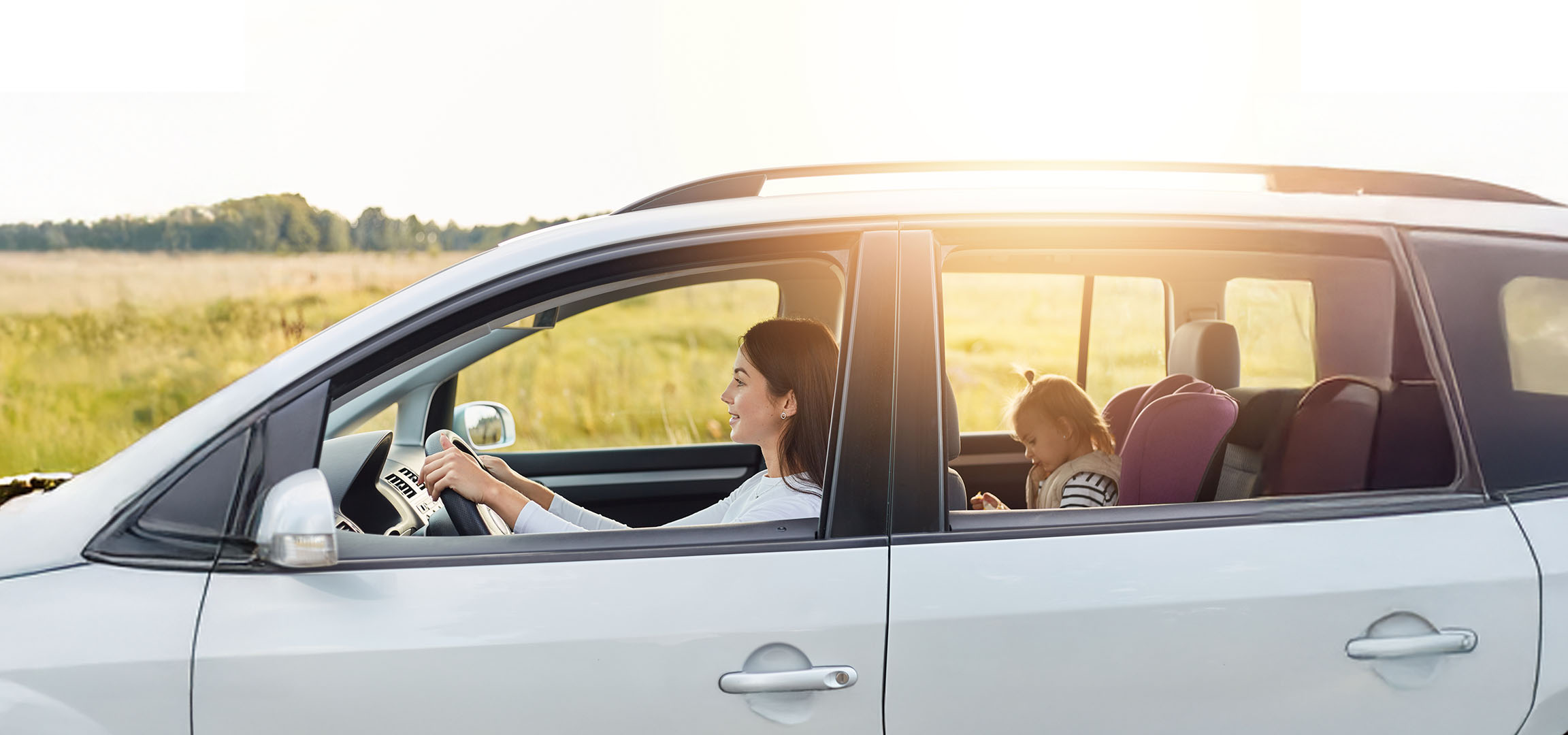 Een vrouw rijdt een auto met haar dochter op de achterbank.