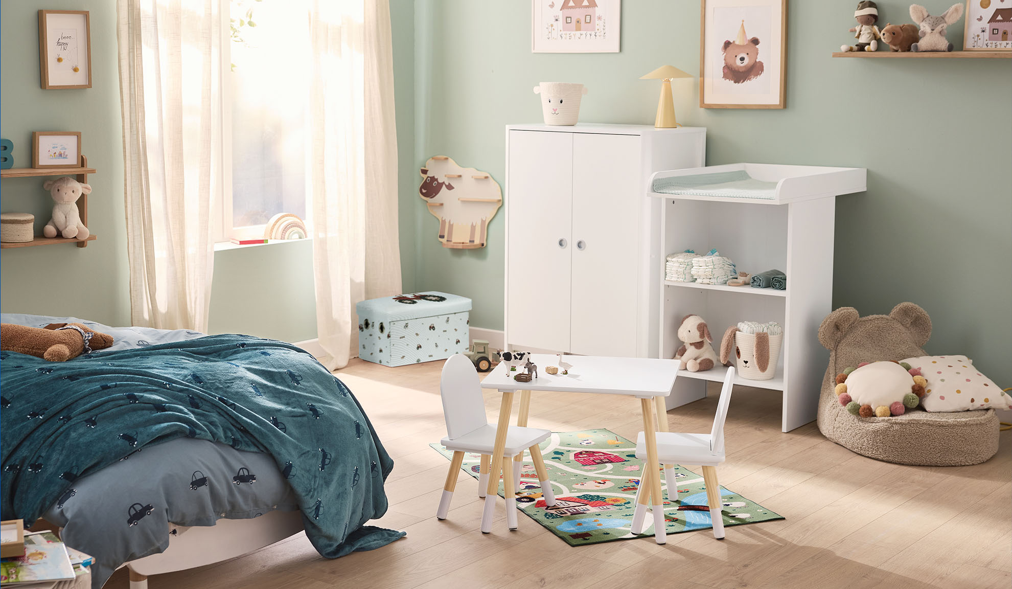 Kinderkamer met bed, commode, kledingkast en speeltafel met stoelen.