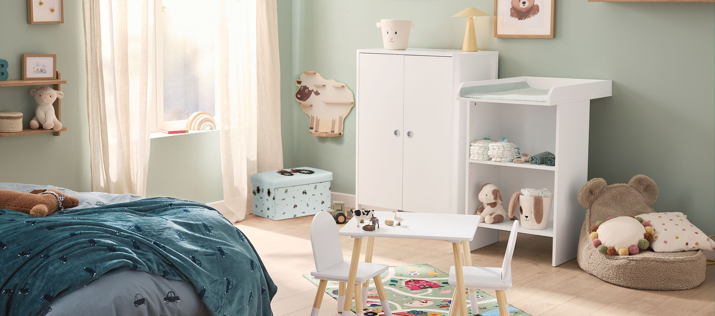 Een kinderkamer met een bed, commode, kledingkast en een kleine tafel met stoelen.