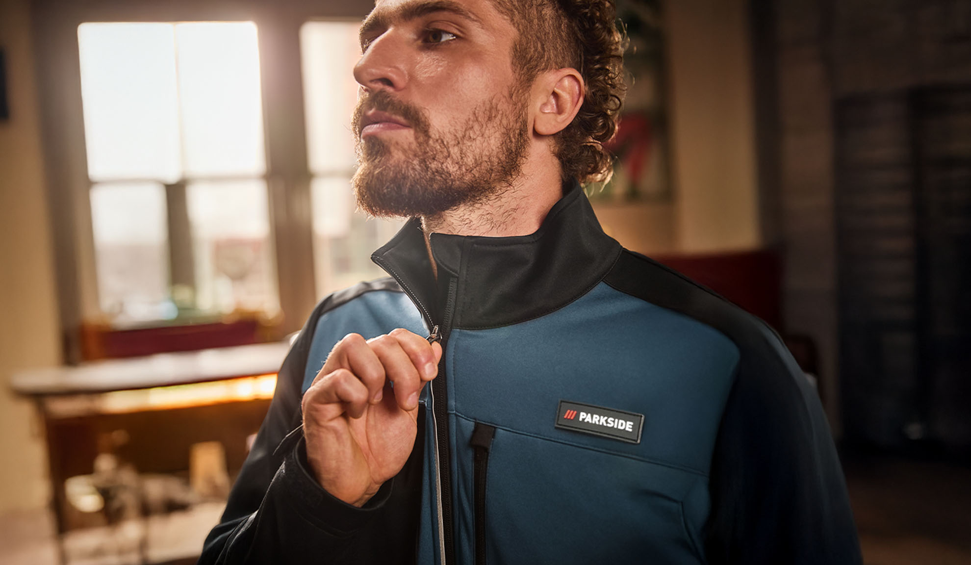 Man in een blauw-zwarte Parkside werkjas, die hij dichtritst.