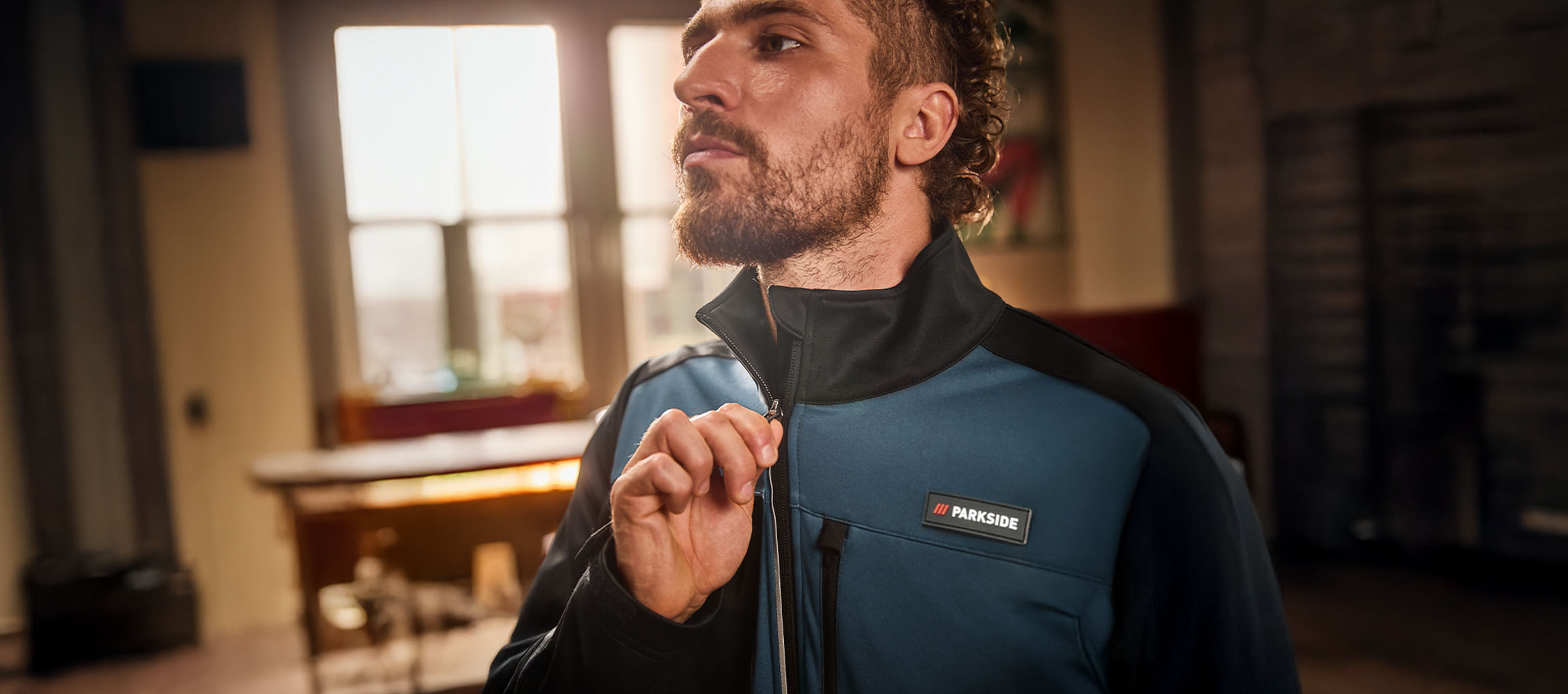 Man in een blauw-zwart Parkside werkjack dat hij dichtritst