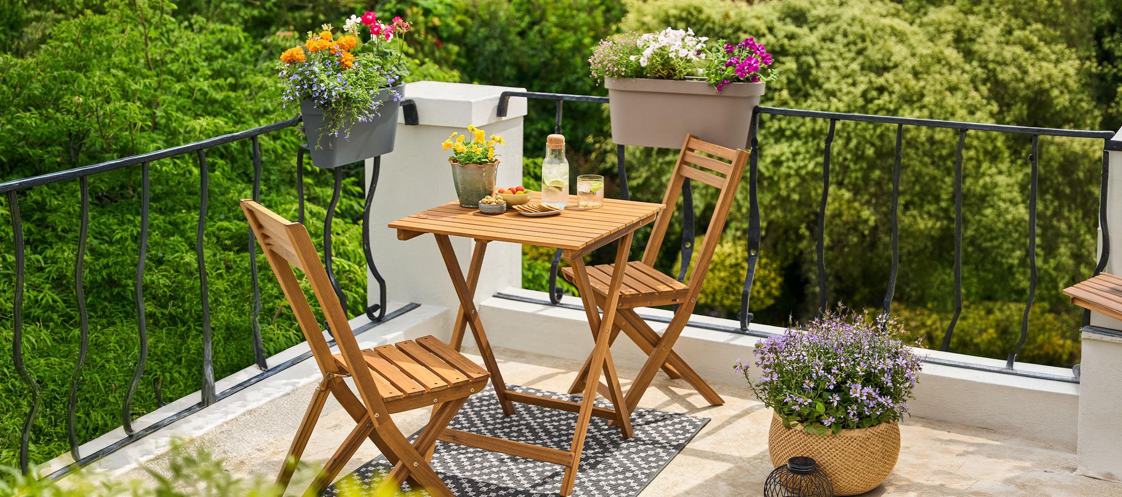 Balkonset met opklapbare tafel en stoelen, versierd met bloempotten.