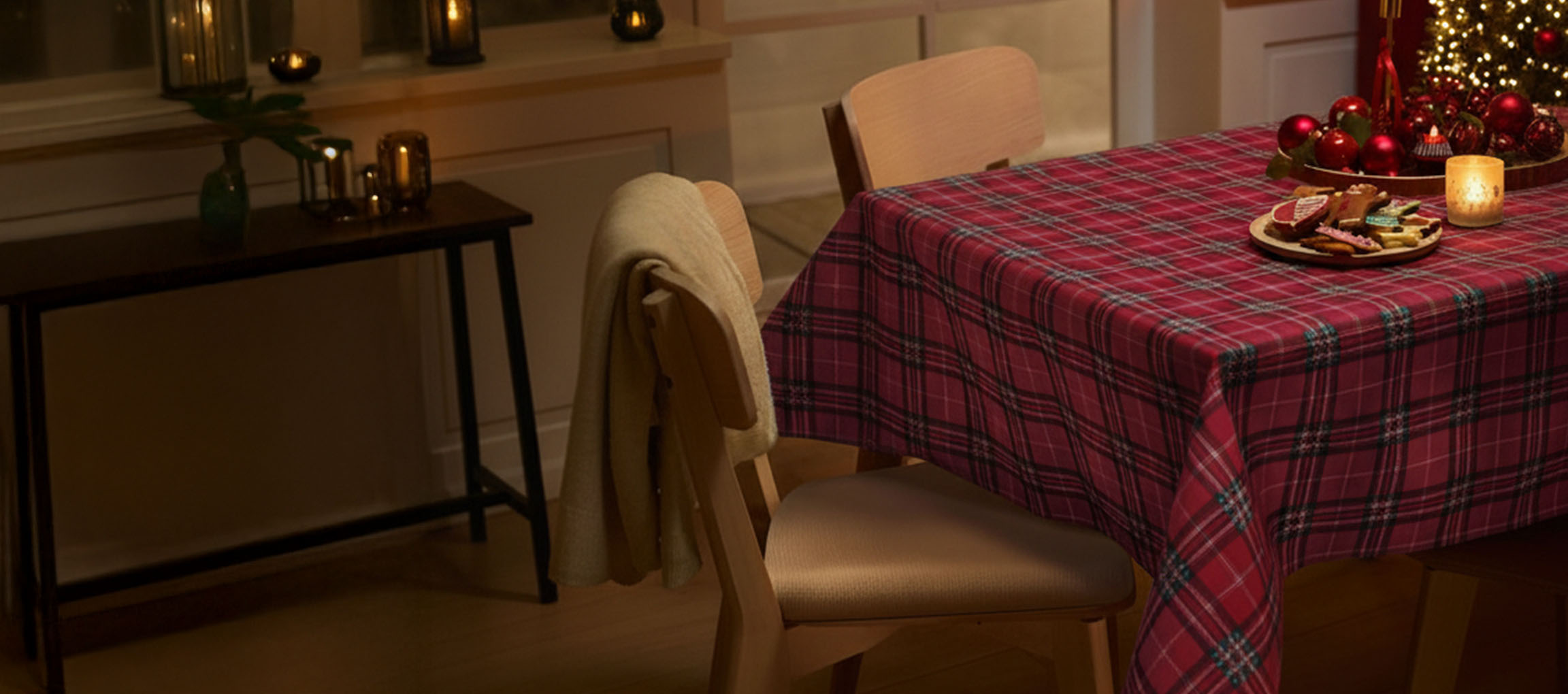 Kersttafel met rood geruit tafelkleed, stoelen en kerstkoekjes.