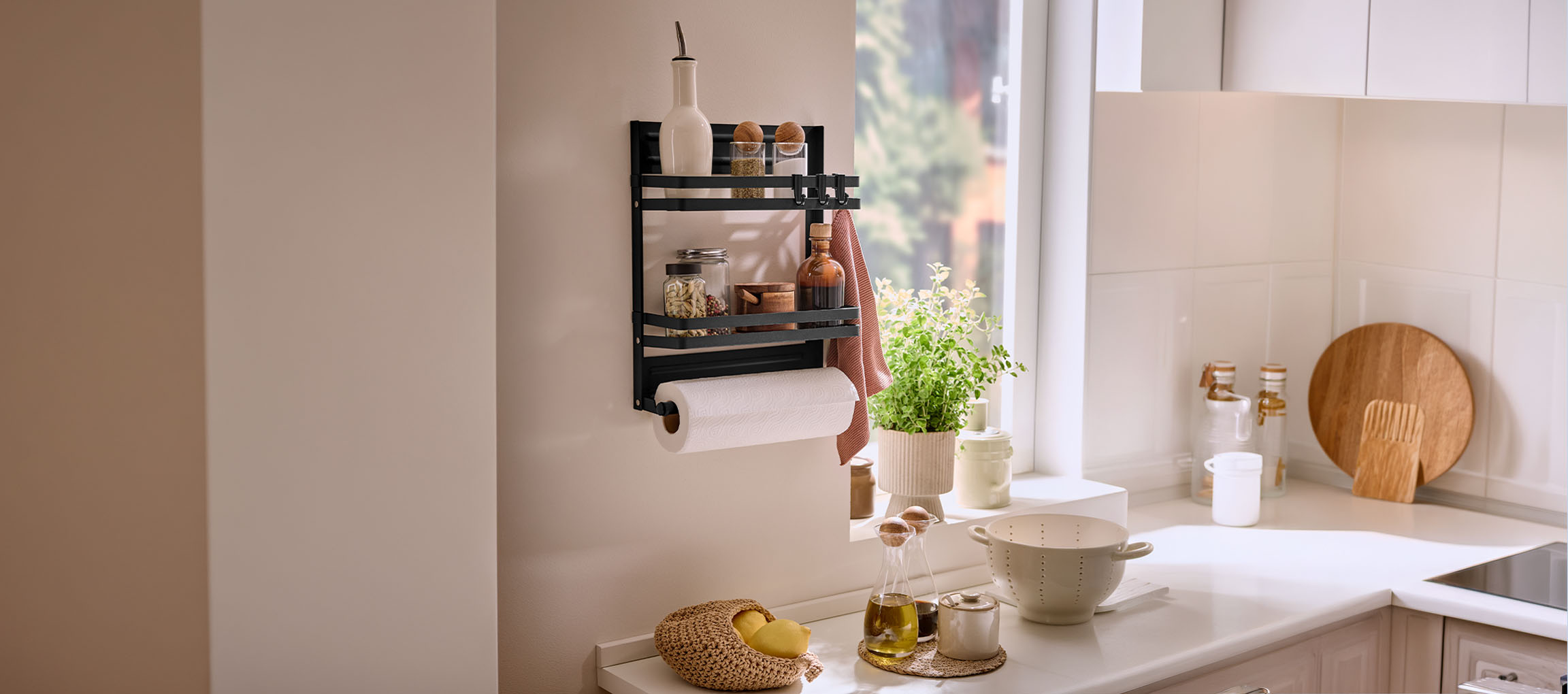 Zwart wandrek voor kruiden met keukenrolhouder in een lichte keuken.