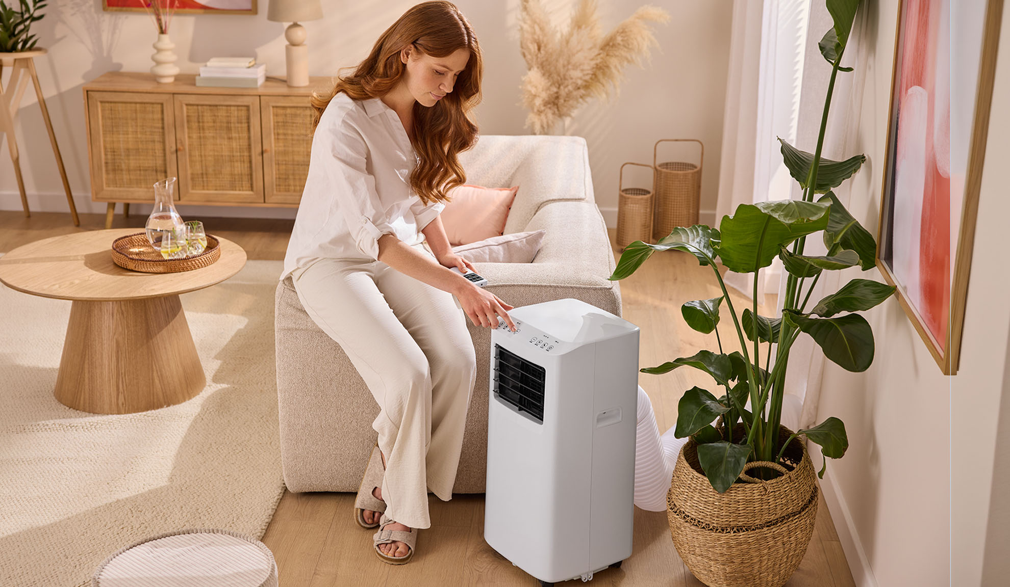 Vrouw stelt draagbare airconditioner in in een gezellige woonkamer.