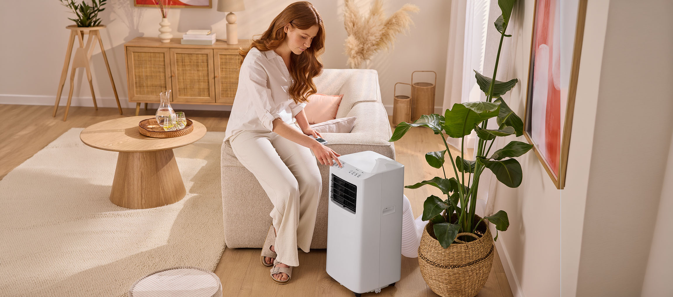 Vrouw stelt draagbare airconditioner in in woonkamer met bank en salontafel.
