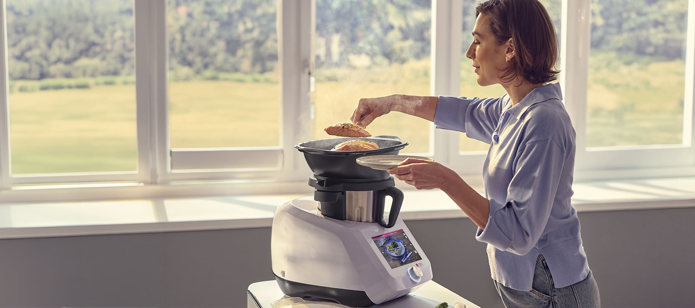 Vrouw kookt met een keukenmachine, stoommand en zalm.