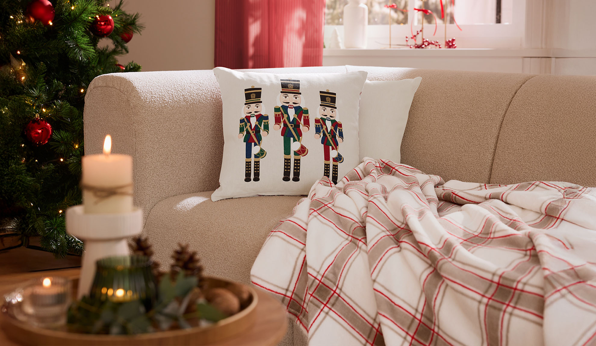 Kerst woonkamer met bank, notenkraker kussens, geruite plaid en kaarsen.