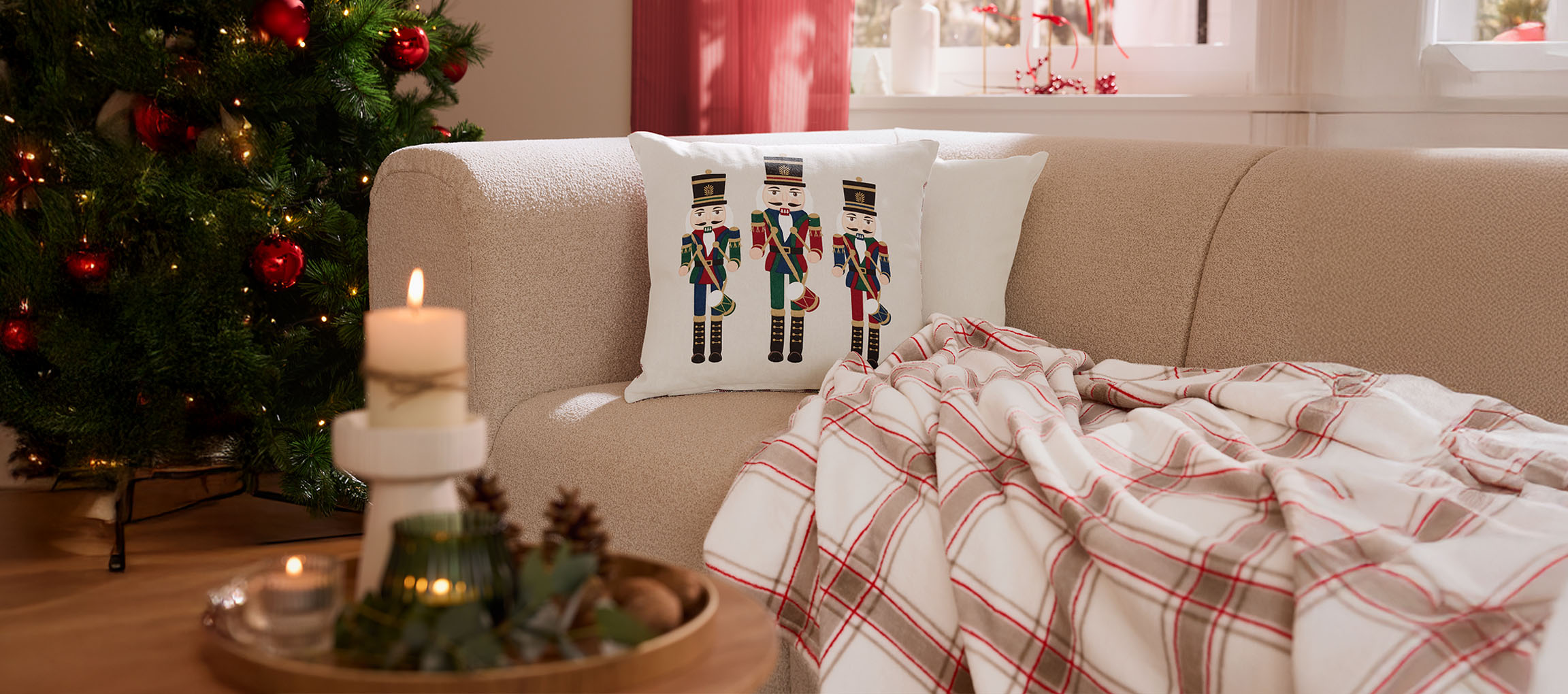 Kerst woonkamer met notenkraker kussen, geruite plaid en kaarsen.