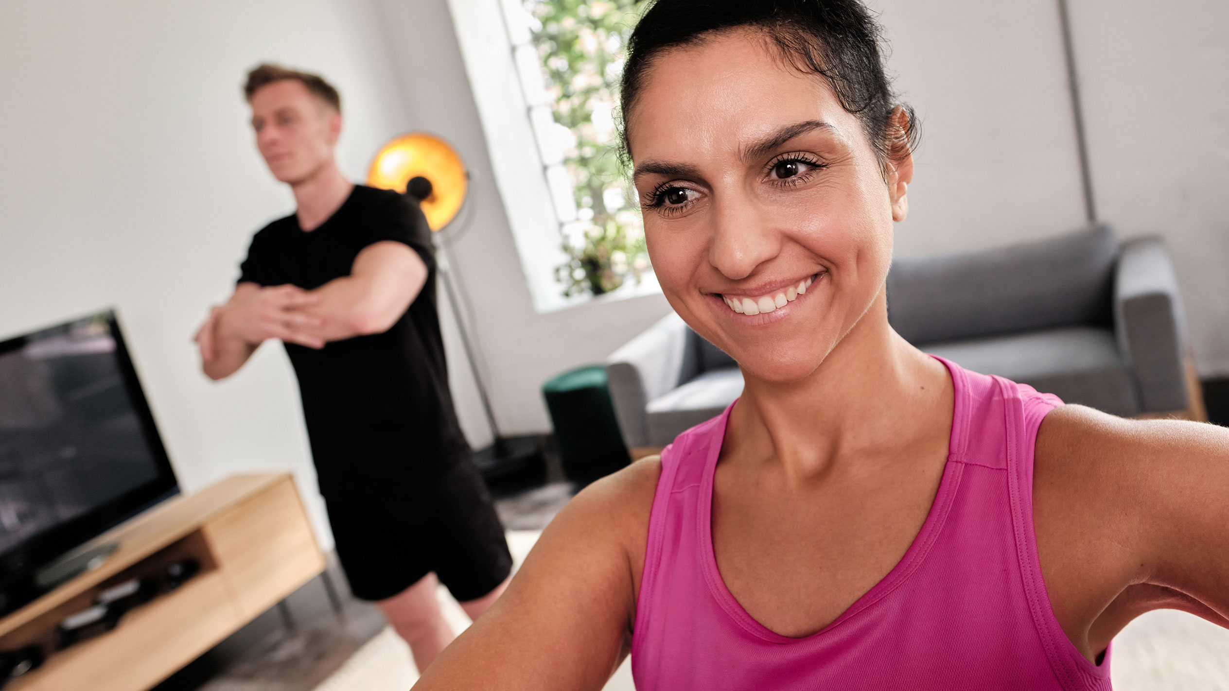 Lachende vrouw die thuis sport met haar partner.