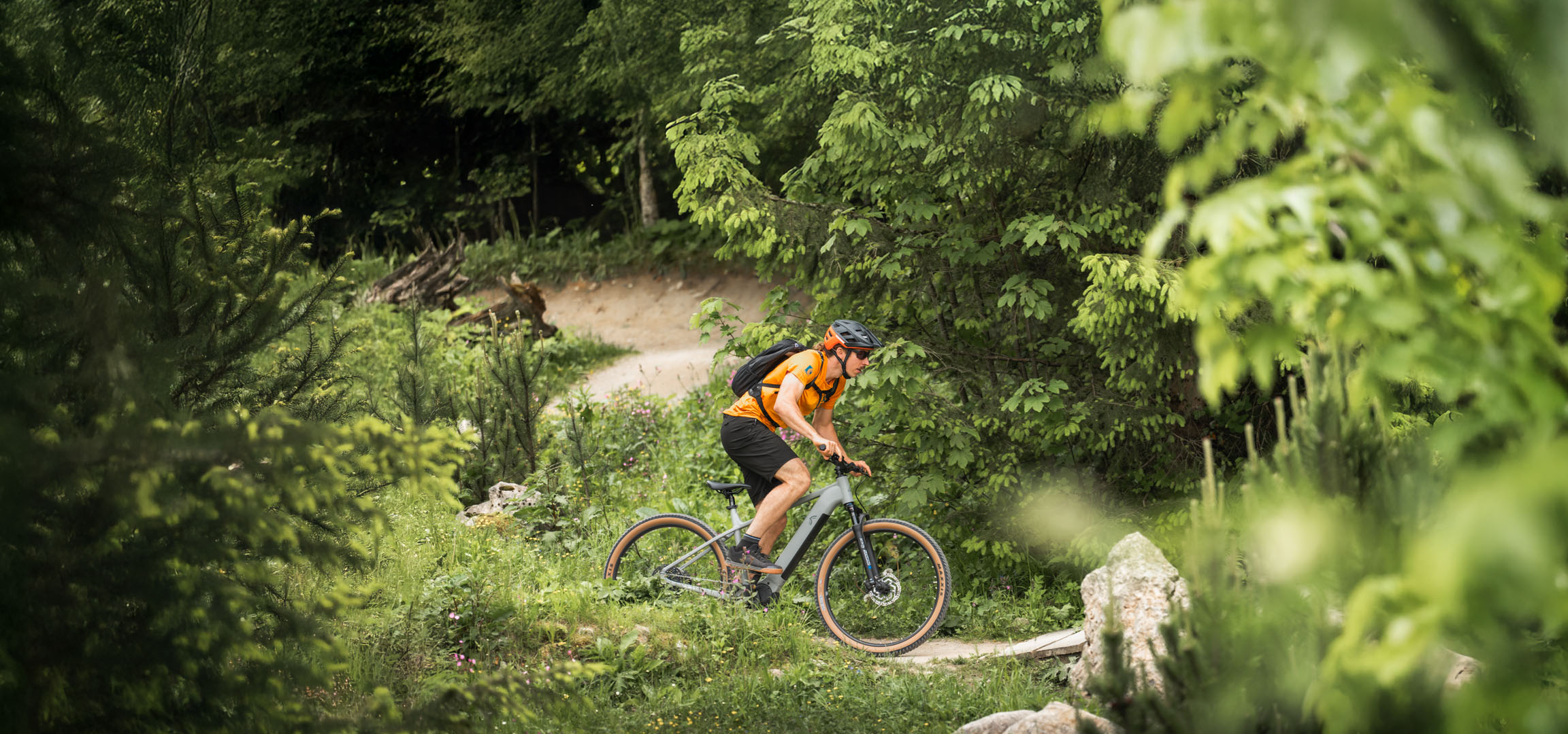 Een fietser geniet van een ritje op een elektrische fiets over een bospaadje.