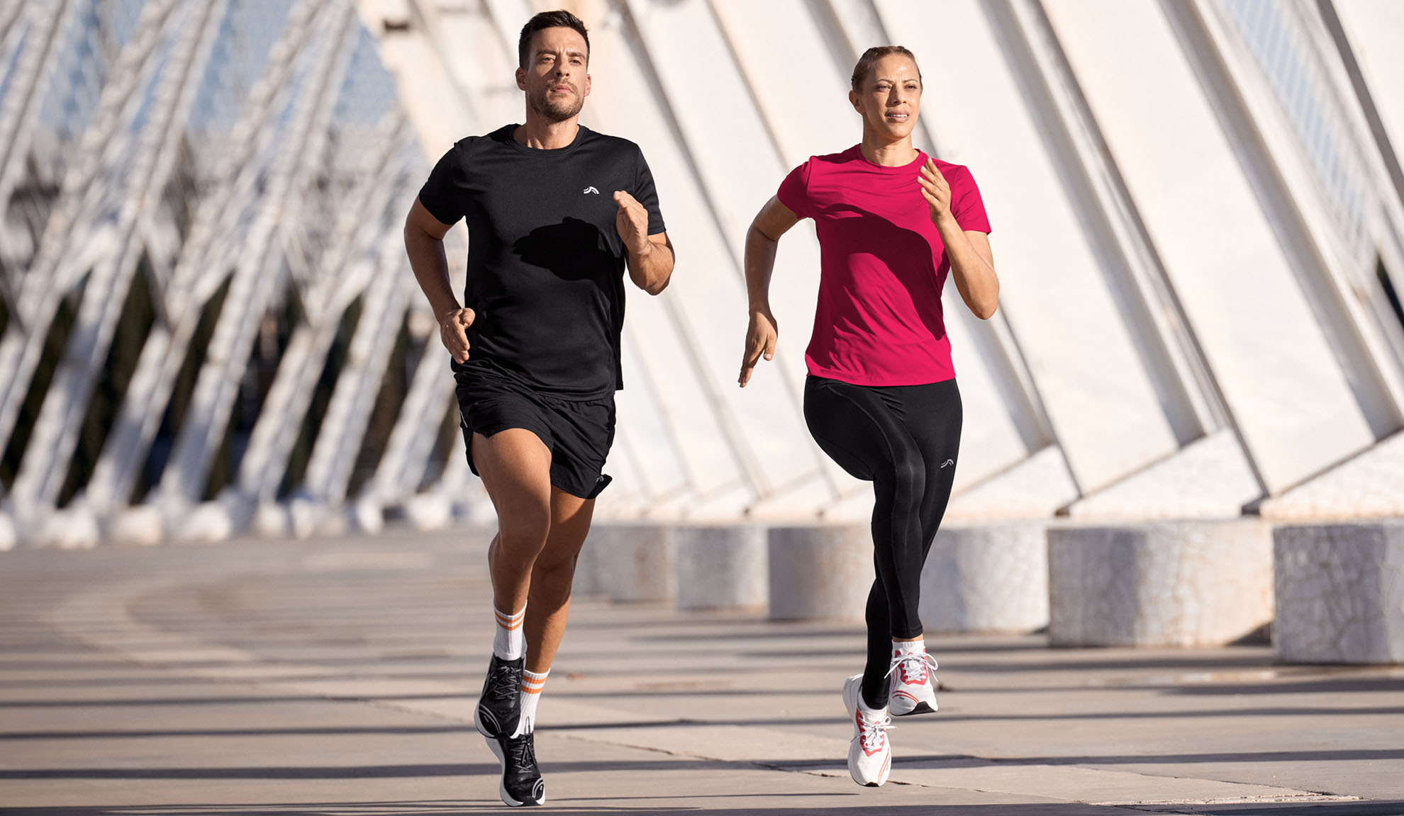 Man en vrouw rennen in sportkleding, T-shirts en leggings.