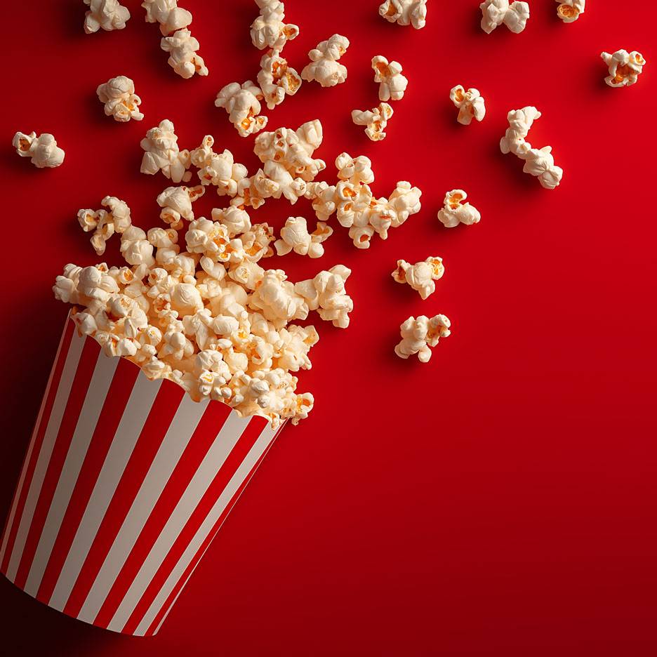 Popcorn op een rode achtergrond, deels in een gestreepte kartonnen beker.