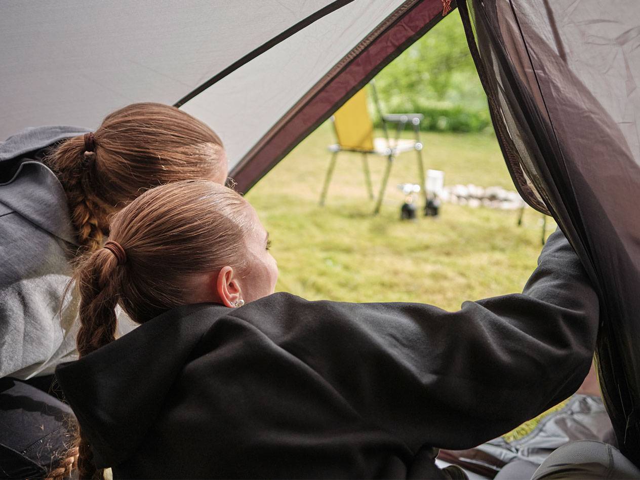 Twee meisjes kijken door de opening van een tent.