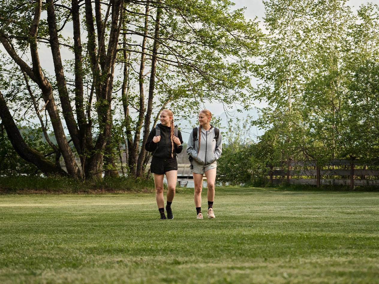 Twee meisjes met rugzakken lopen over een gazon.