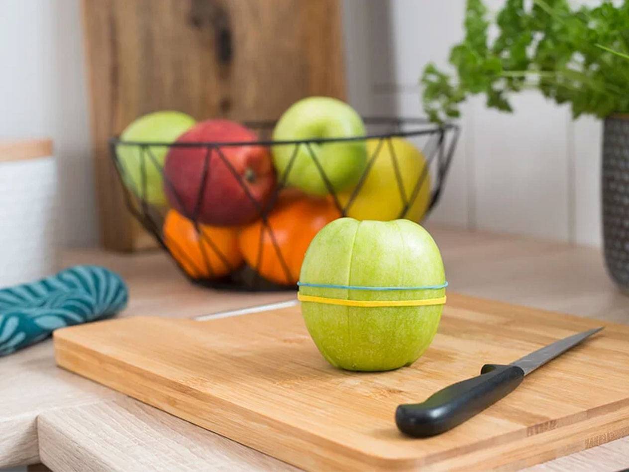 Appel vastgemaakt met elastiekjes op een houten snijplank.