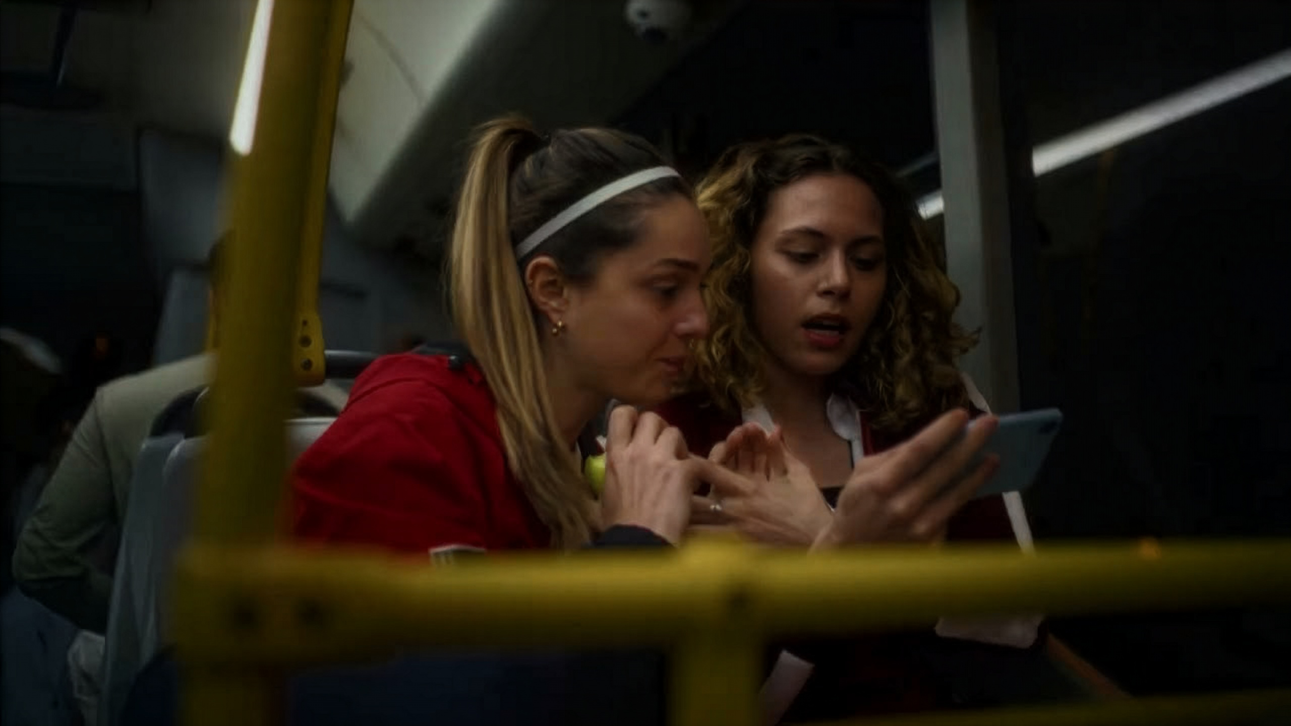 Twee vrouwen kijken naar een smartphone in een bus.